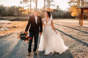 Walk hand-in-hand across the farm grounds of Whispering Pines, with the serene pond and vibrant trees in the background on a crisp fall day