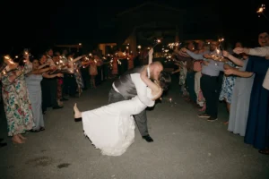 Kelsey and Andrew share a kiss, surrounded by guests holding sparklers, outside the barn at during their wedding send-off.