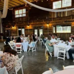 Guests relax under twinkling string lights in the barn-style reception hall