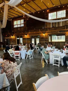 Guests relax under twinkling string lights in the barn-style reception hall