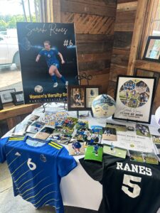 A memory table at Sarah’s graduation party showcasing her soccer jersey, a signed soccer ball, framed photos, and awards.