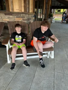 Two boys sitting on a wooden swing bench on a porch at Peyton’s graduation party.