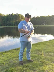 A man fishing by a serene lake at Peyton’s graduation party