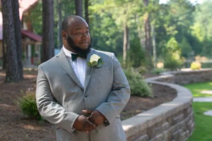 The groom stands outside at Whispering Pines, looking ahead with anticipation before the wedding ceremony.