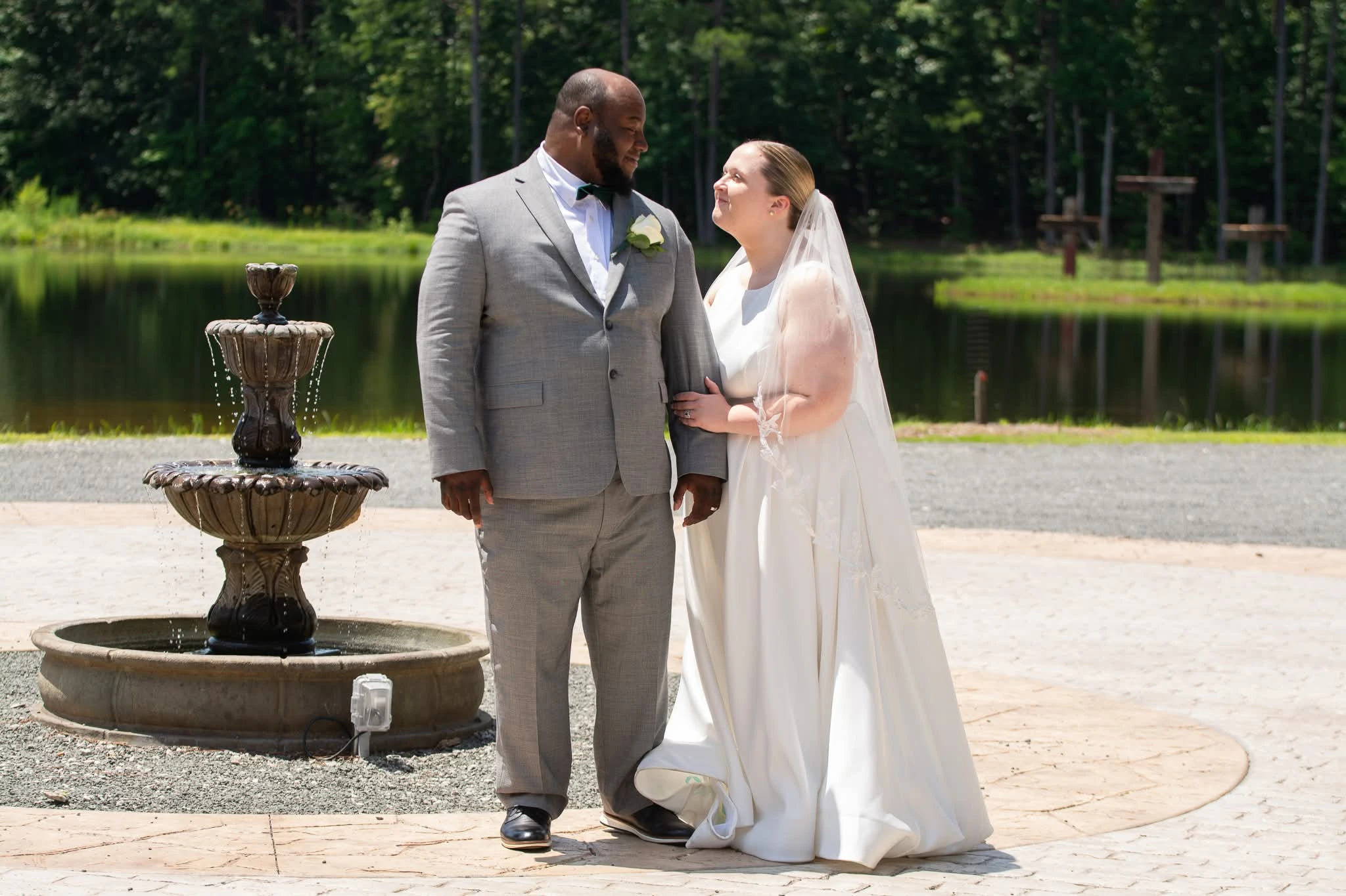 The bride and groom share a joyful moment by the fountain at Whispering Pines, a wedding venue in Henderson.