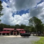 A helicopter landed in front of a rustic barn at Whispering Pines Venue.