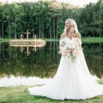 Callie Reaves glowing in her bridal portrait at Whispering Pines Venue, surrounded by lush pine trees and soft natural light.