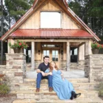Ryan and Jordan posing together in front of the rustic barn at Whispering Pines Venue during their engagement session.