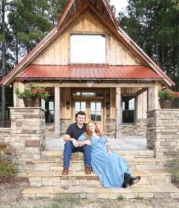 Ryan and Jordan posing together in front of the rustic barn at Whispering Pines Venue during their engagement session.