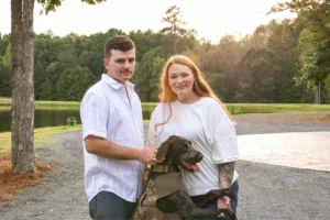 Ryan and Jordan posing romantically by the peaceful pond at Whispering Pines Venue, framed by golden light and open fields in the serene Vance County countryside