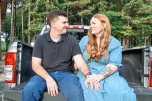 Ryan and Jordan sitting together in the back of his truck, laughing and enjoying a relaxed engagement photo at Whispering Pines Venue.