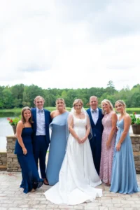 Bride and her family posing together in front of the lake at Whispering Pines Venue in Henderson, North Carolina.