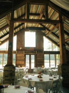 Rustic wedding venue at Whispering Pines decorated with burgundy accents, red roses, and sunflowers for a fall-inspired wedding reception.