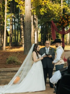 Logan and Leanne exchanging vows during their outdoor wedding ceremony at Whispering Pines surrounded by fall-inspired décor.