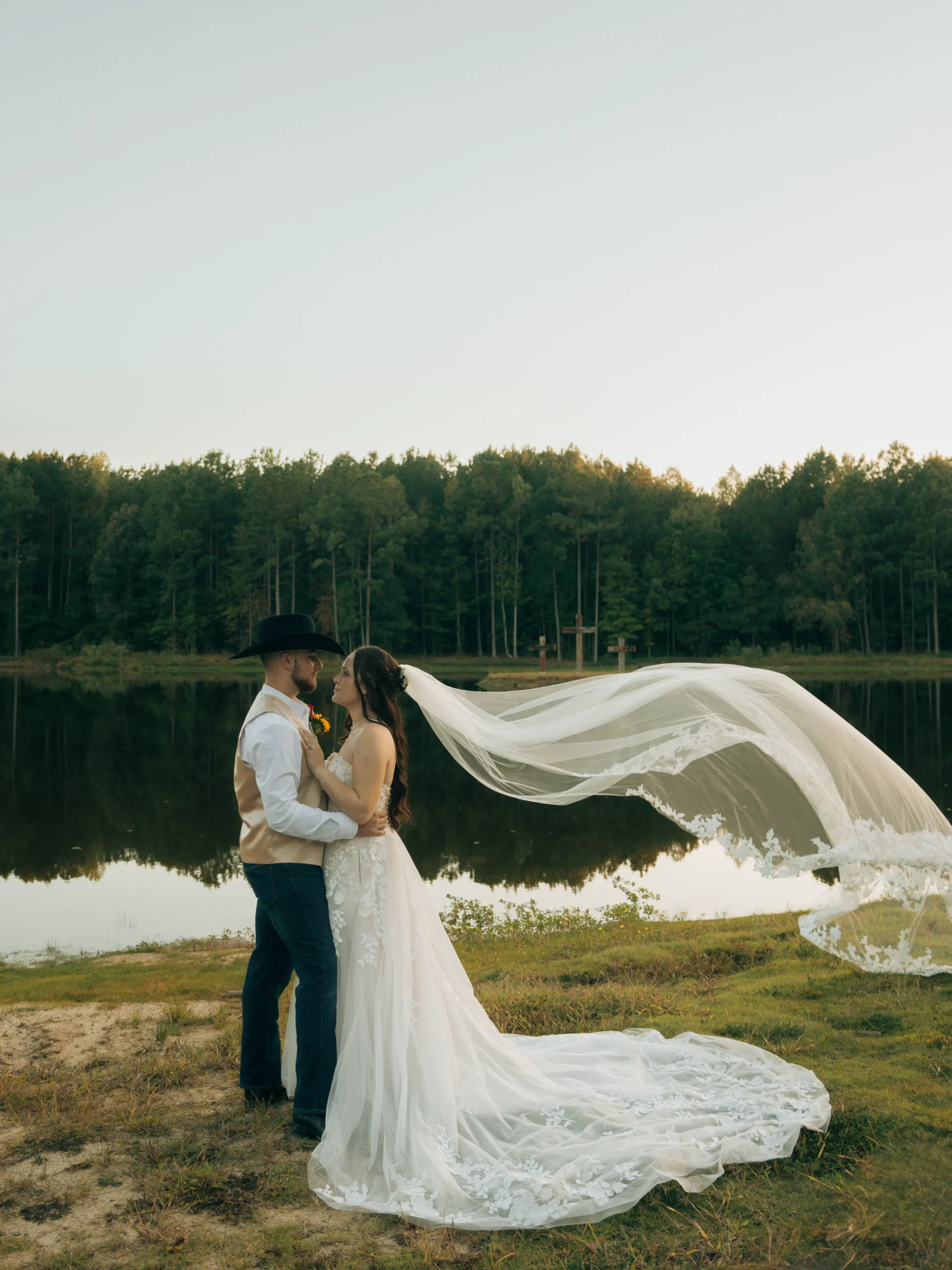 Bride and groom Logan and Leanne posing together in front of the lake at Whispering Pines wedding venue on their wedding day.