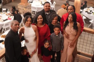 Derrick and Elethia posing with their family and friends, all smiling and celebrating their first wedding anniversary at Whispering Pines Venue.