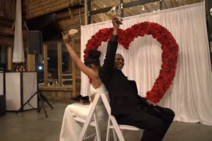 Derrick and Elethia sitting back-to-back at their anniversary reception, laughing and enjoying the intimate celebration in a beautifully decorated space.