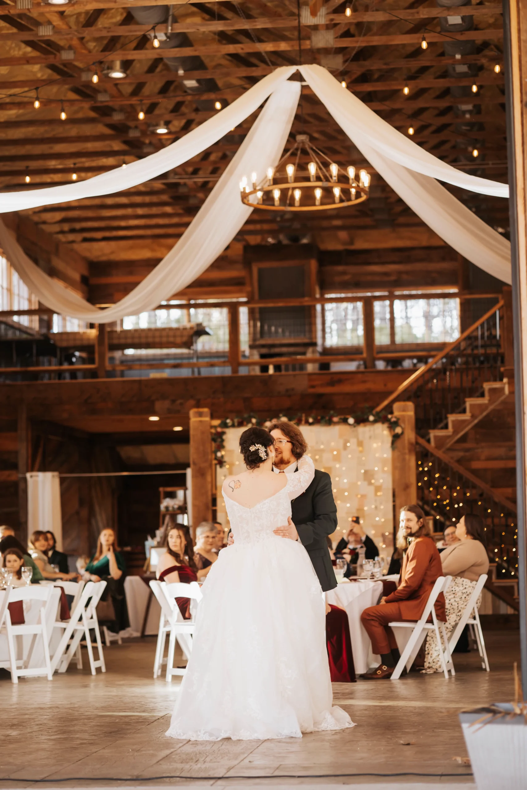 Newlywed couple sharing their first dance during an intimate wedding reception at Whispering Pines Venue in Henderson, NC with a warm and romantic winter atmosphere.