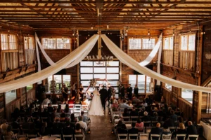Bride and groom exchanging vows during a romantic winter wedding ceremony inside the rustic barn at Whispering Pines Venue.