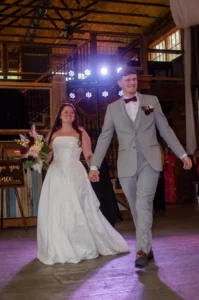 Bride and groom make their grand entrance into the reception at Whispering Pines Venue, celebrating their April wedding in a beautifully decorated rustic barn near Henderson, NC.