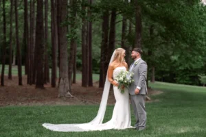 Bride and groom sharing a quiet moment beneath towering pine trees during their wedding at Whispering Pines Venue in Henderson, NC.