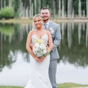 Bride and groom Chris and Lana posing outside Whispering Pines Venue in Henderson, NC, with the bride's long veil flowing behind them.