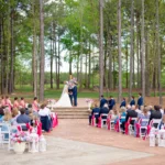 Wedding ceremony at Whispering Pines Venue with guests seated and watching the bride and groom exchange vows.