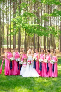 Bride posing with her bridesmaids wearing hot pink dresses during a wedding celebration at Whispering Pines Venue.